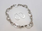 un gros plan sur un bracelet à chaîne en argent accompagné d'une paire de boucles d'oreilles