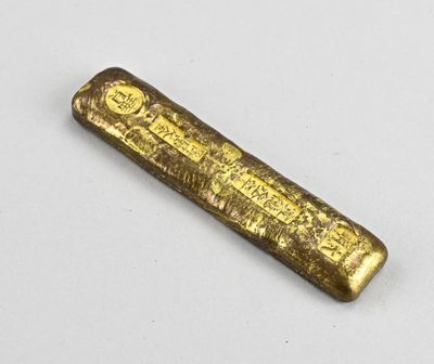 un vieux lingot d'or posé sur une surface blanche
