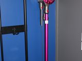 un aspirateur rose à fil, dans un coin d'un mur bleu