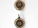 two gold tone earrings on a white surface with a white background