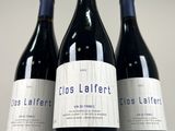 three bottles of red wine sitting on top of a white table