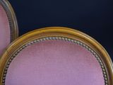 pair of pink chairs with gold trim and beading on the back
