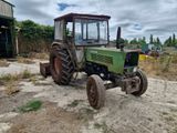 a green tractor that is parked in the dirt