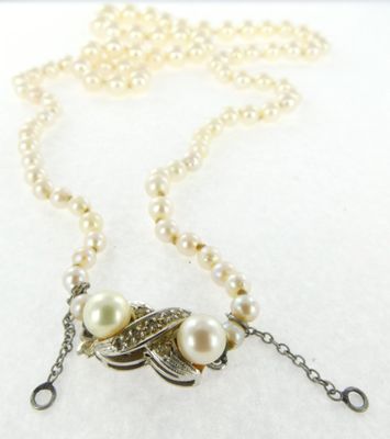 collier avec des perles et un pendentif en forme de feuille sur fond blanc