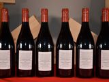 six bottles of red wine are lined up on a table