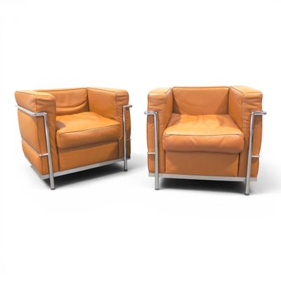 pair of orange leather armchairs with chrome legs on a white background