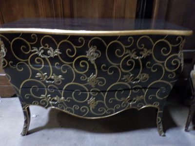 a black and gold chest of drawers next to a chair