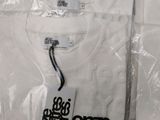 a white t - shirt with a tag on it sitting on a table