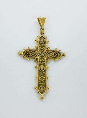 un pendentif en forme de croix en or, orné d'un motif en filigrane sur fond blanc