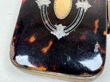 a tortoise shell case with a gold emblem on it