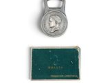 une vieille pièce de monnaie à laquelle est fixé un décapsuleur