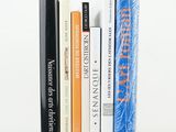 several books are stacked on top of each other on a white surface