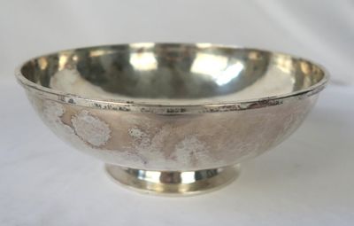 un bol en argent posé sur une table avec un fond blanc
