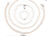a close up of a necklace and bracelet with pearls on a white background