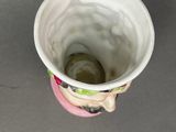 a white cup with a pink handle sitting on a table