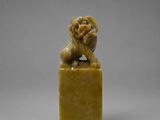 une petite figurine sculptée représentant un lion posée sur un socle