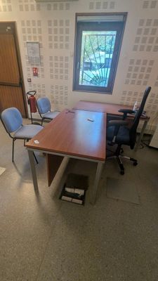 une photo d'un bureau vide avec un bureau et des chaises