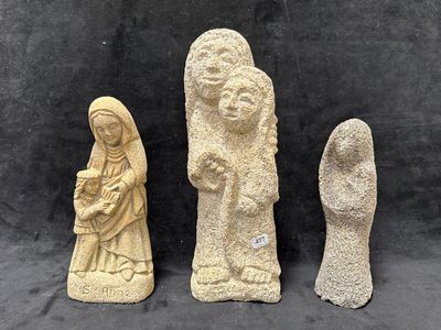 trois statues en pierre représentant une femme, un homme et un enfant, sur fond noir
