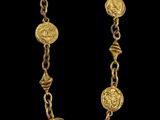un collier en or composé de pièces suspendues à une chaîne, sur fond noir