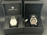 two watches in a box with a tag on the side of the watch
