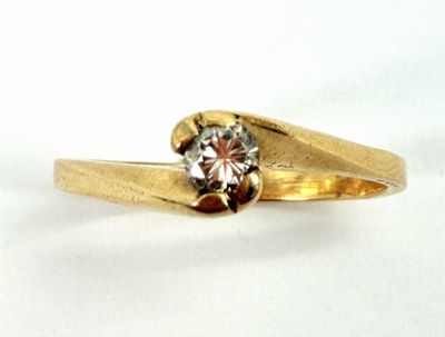 a gold ring with a diamond in it on a white surface