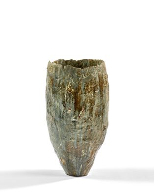 un vase vert posé sur une surface blanche