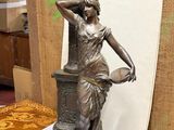 a bronze statue of a woman holding a basket