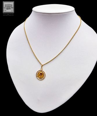 un collier en or orné d'une pierre orange sur un mannequin blanc