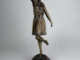 une statue en bronze représentant une femme tenant une raquette de tennis