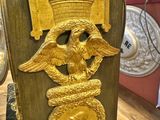 a gold clock with an eagle and a snake on it