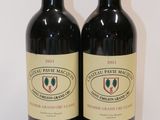 two bottles of red wine sitting on top of a white table