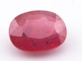 a close up of a red ruby stone on a white surface