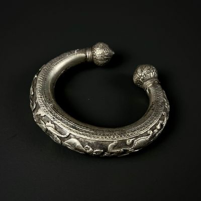 gros plan d'un bracelet en argent sur une surface noire