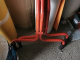 a red pipe on a metal stand next to a yellow pole
