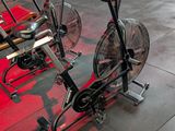 a gym with a row of exercise bikes and a fan