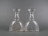 pair of clear glass vases sitting on top of a gray surface