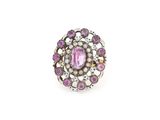 un gros plan d'une bague en pierre rose et perle sur fond blanc