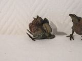 two figurines of birds sitting on a white surface