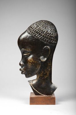 une tête de femme en bronze, avec une chaîne autour du cou