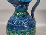 a blue and green vase with a handle on a table