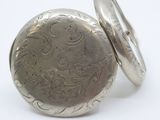 a silver pocket watch sitting on top of a white surface