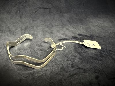 a silver bracelet with a tag on it on a black surface
