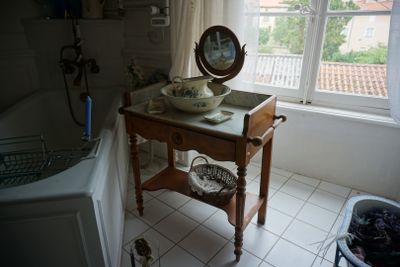 une petite table sur laquelle est posé un miroir, dans une salle de bains