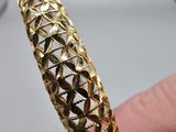 un gros plan sur la main d'une personne tenant un bracelet en or