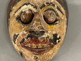 an image of a wooden mask on a stand on a white surface