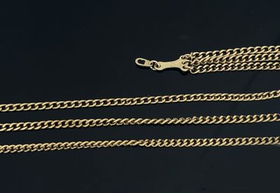 a close up of two gold chains on a black surface