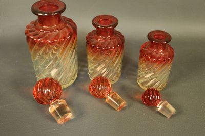 trois vases en verre rouge posés les uns à côté des autres sur une table