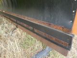 a close up of a rusted metal bench in the grass