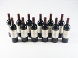 six bottles of wine lined up in a row on a white surface