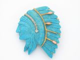 une broche bleue ornée de plumes, posée sur un fond blanc